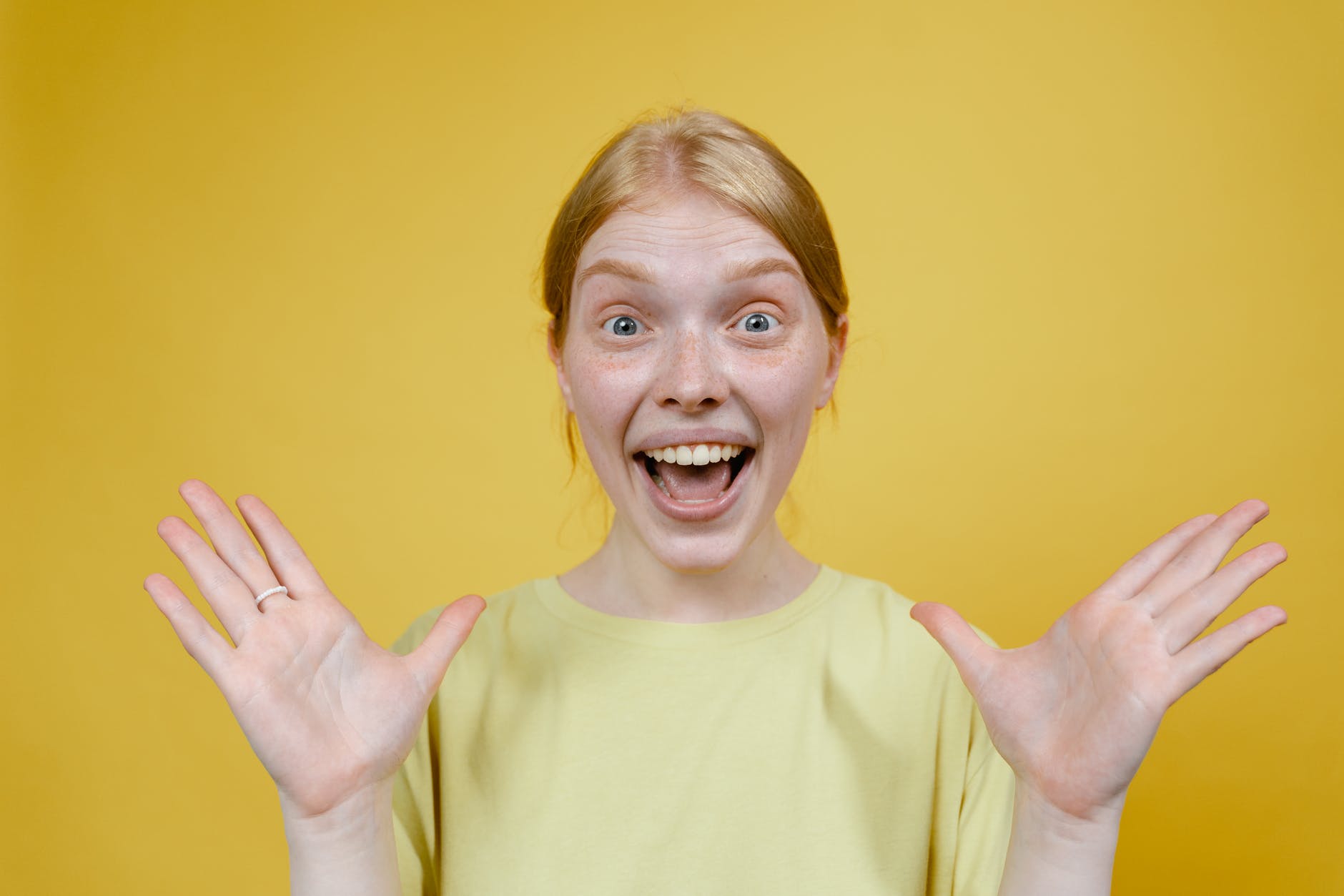 smiling woman in yellow t shirt holding hands apart